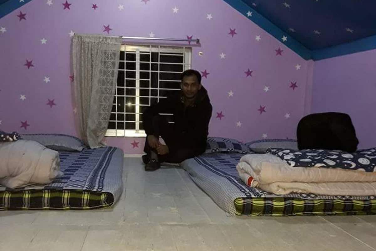 A room with two beds, a window with curtains, and star-patterned walls.