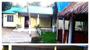 A two-story building with a flat roof, a thatched-roof structure, and a paved entrance. - Nilborno Cottage (Kamalganj)