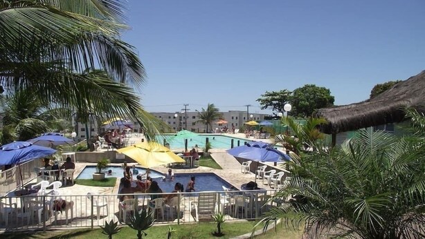 A pool area with multiple swimming pools, umbrellas, and lounge chairs. - Apto Cabo Frio Marina Clube (Sao Pedro da Aldeia)