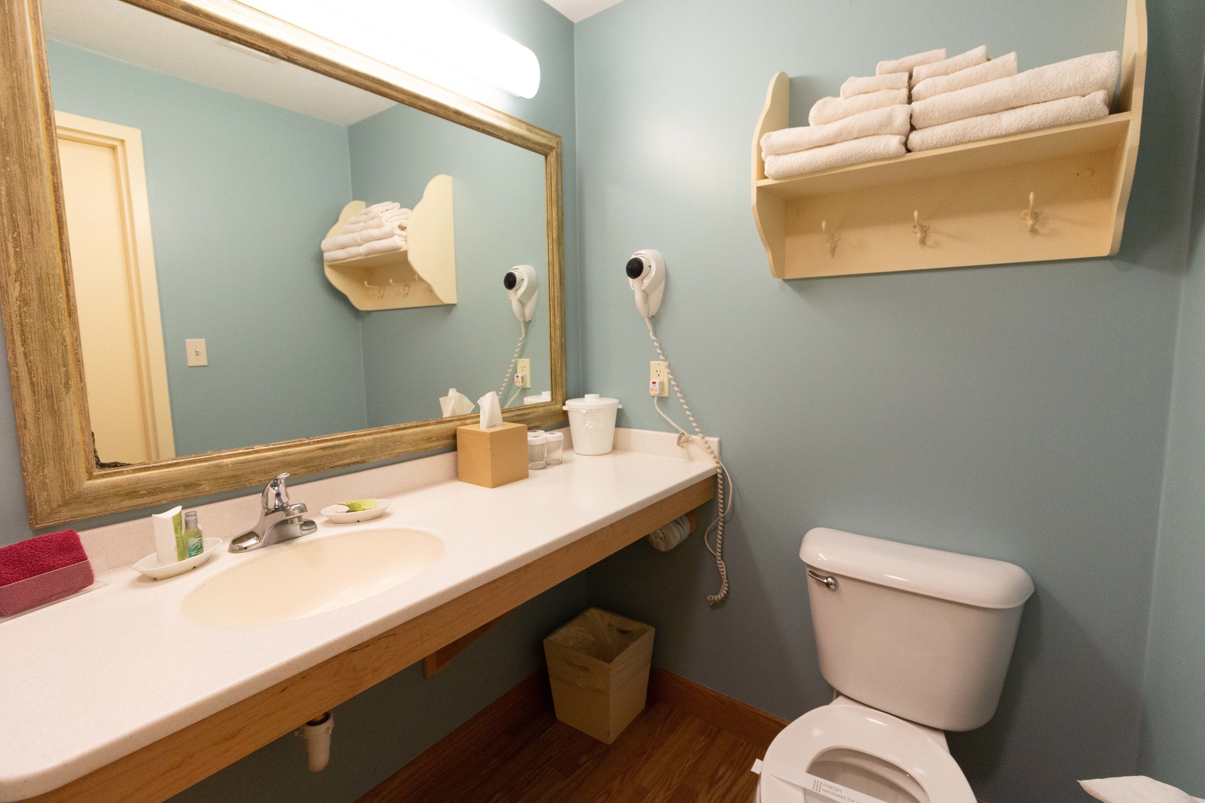 A bathroom with a sink, mirror, towel rack, and toilet.