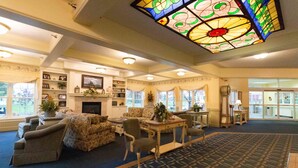 A spacious lobby with a fireplace, comfortable seating, and a stained glass ceiling.