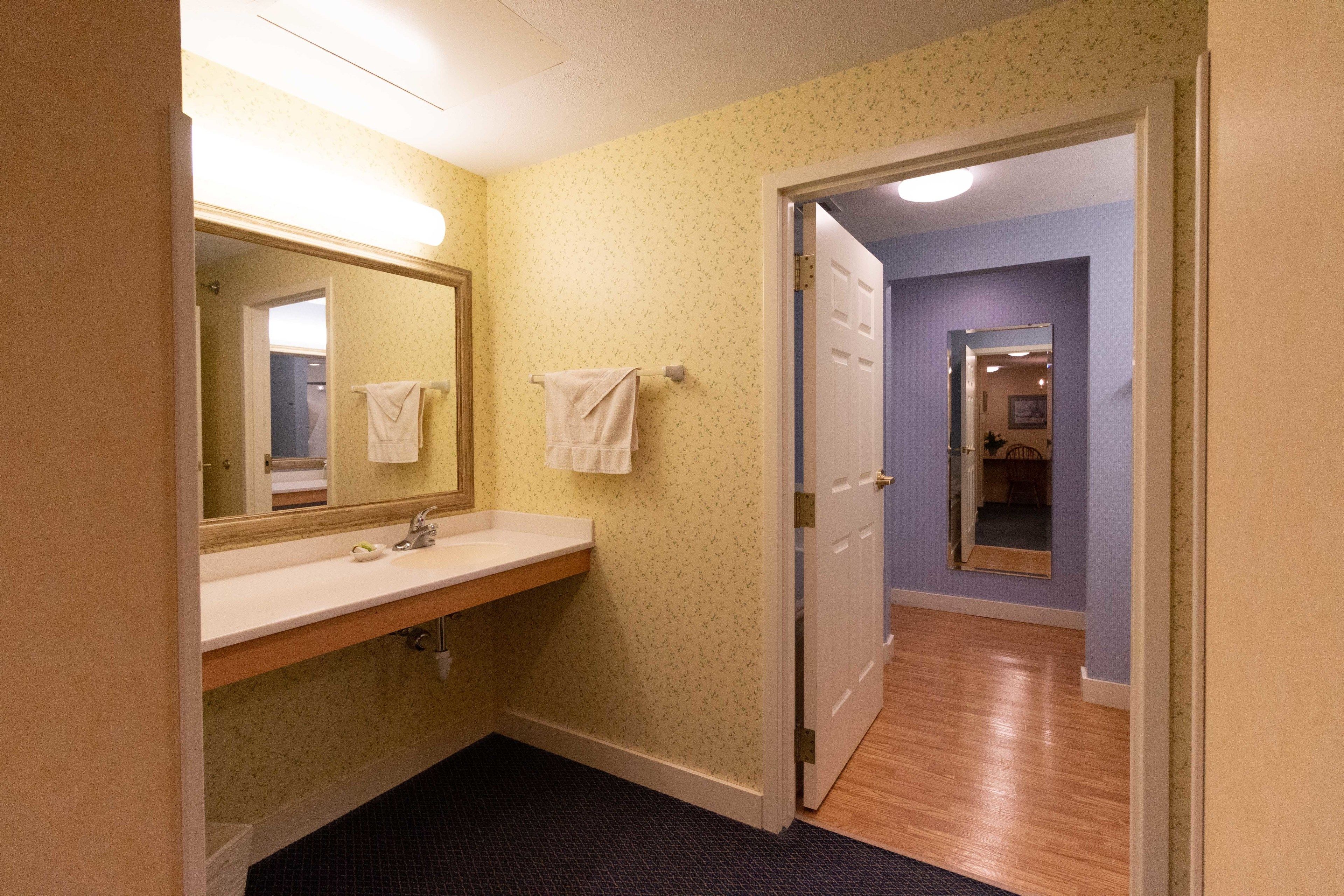 A bathroom with a sink, mirror, and two towels hanging on the wall.