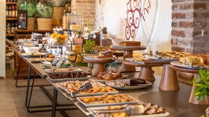 Une table de buffet garnie de divers plats, avec un mur de briques en arrière-plan.