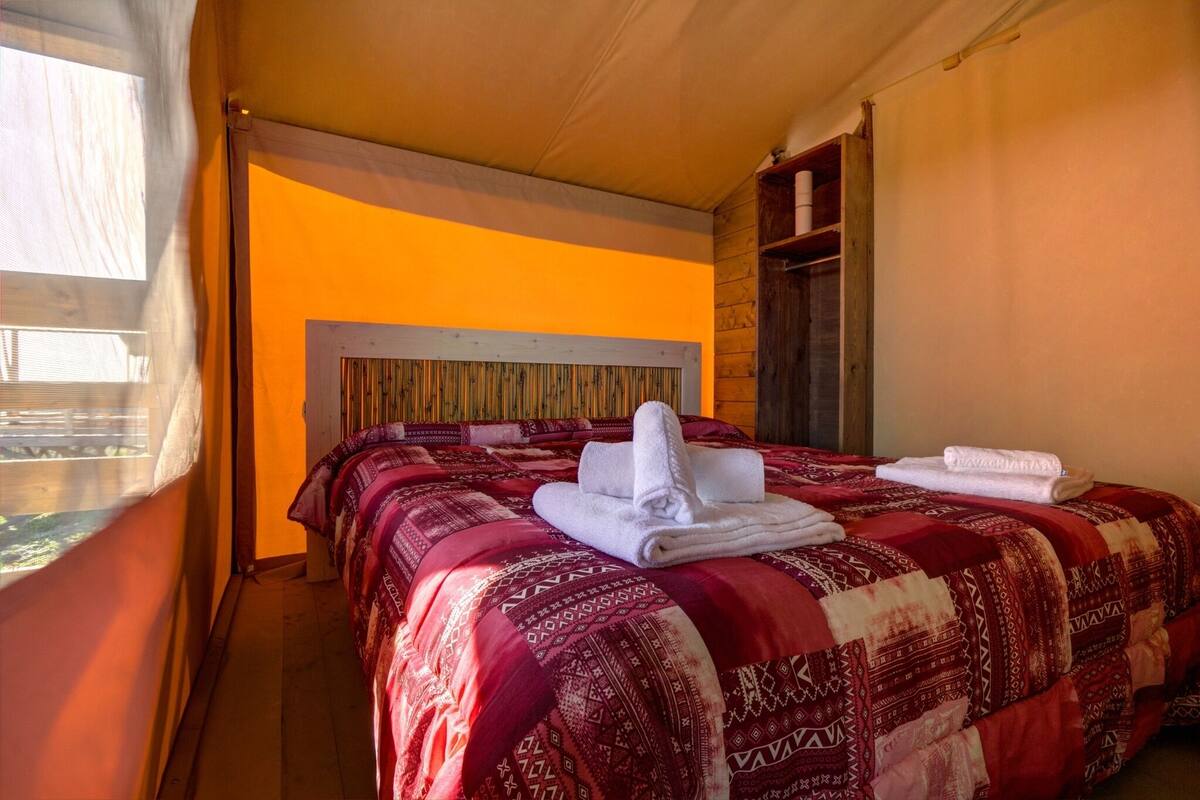 Habitación de hotel con una cama grande, cabecero de madera, ventana con cortinas y armario de madera.