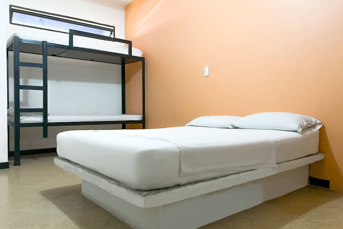 A bunk bed with a mattress and pillows, a window, and a wall switch.