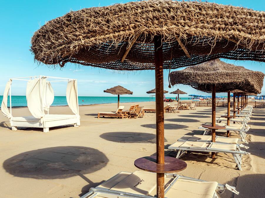 Praia particular, areia branca, espreguiçadeiras, guarda-sóis