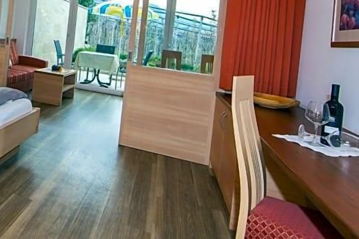 A hotel room with a bed, bedside tables, a desk, and a view of the outdoors.
