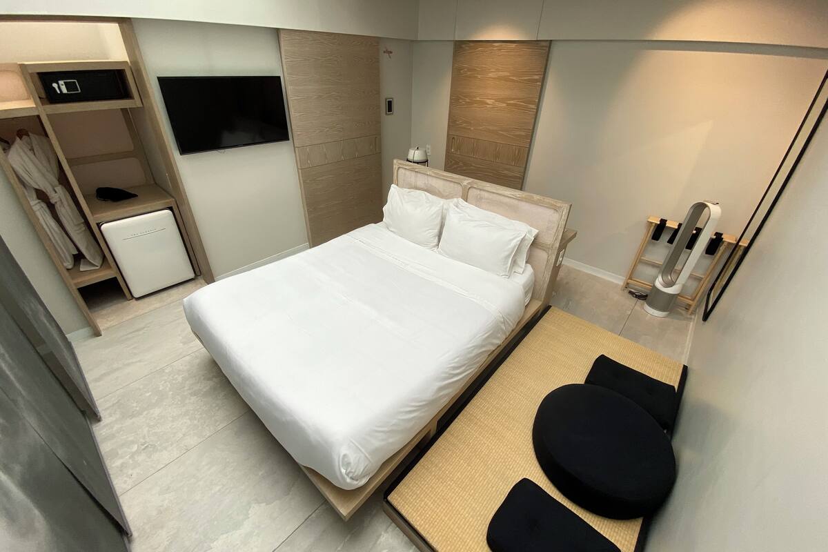 A modern bedroom with a large bed, a bedside table, a small bedside unit, a TV, and a mirror.