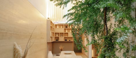 A modern interior with a wooden reception desk, seating area, and a wall-mounted shelf with decorative items.
