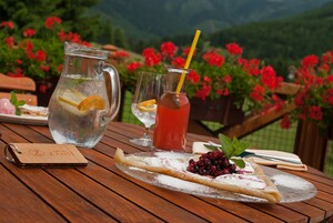 A wooden table with a dessert plate, a pitcher, and two glasses of beverages.