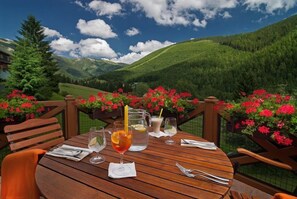 A wooden table set outdoors with drinks and a scenic mountain view. - Zatisi (Spindleruv Mlyn)