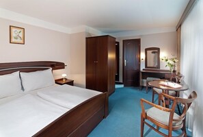 A hotel room with a large bed, a desk with a chair, a small table with a lamp, and a mirror. - Zatisi (Spindleruv Mlyn)