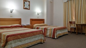 A hotel room with two beds, a desk, a chair, and a window with curtains. - Hotel Astromundo (Reynosa)