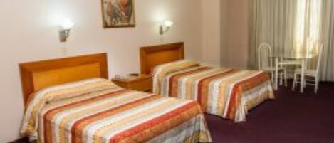 Habitación de hotel con dos camas, un escritorio y una silla.