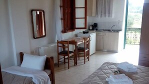 Ein Zimmer mit zwei Betten, einer kleinen Küchenzeile, einem Essbereich und einem Fenster mit Aussicht.