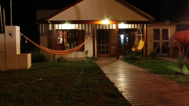 Una casa con terraza de madera que da a un porche cubierto, una hamaca y un tobogán.