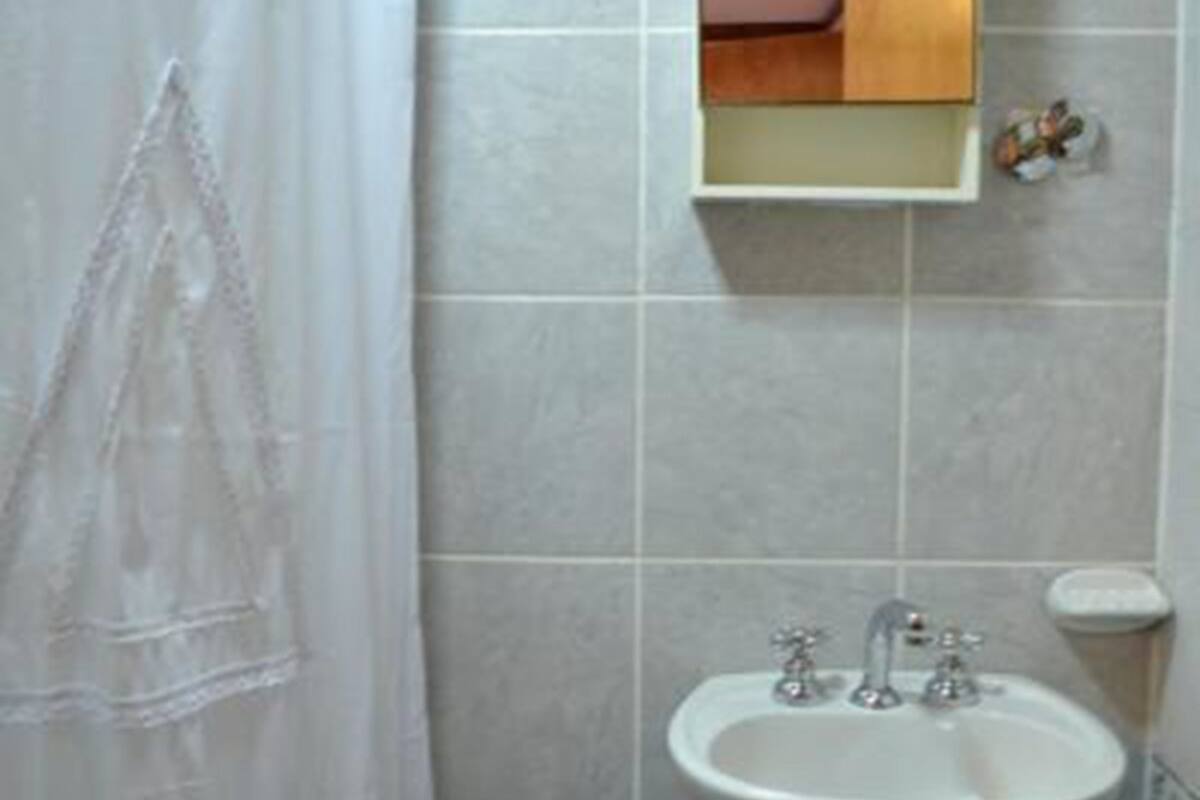 A bathroom with a white sink, a mirror, and a shower curtain.