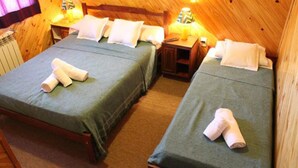 Una habitación acogedora con dos camas, cada una con una colcha verde y almohadas blancas, y un cabecero de madera.