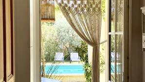 A doorway leading to a pool area with a macramé curtain, outdoor seating, and a clear view of the pool.