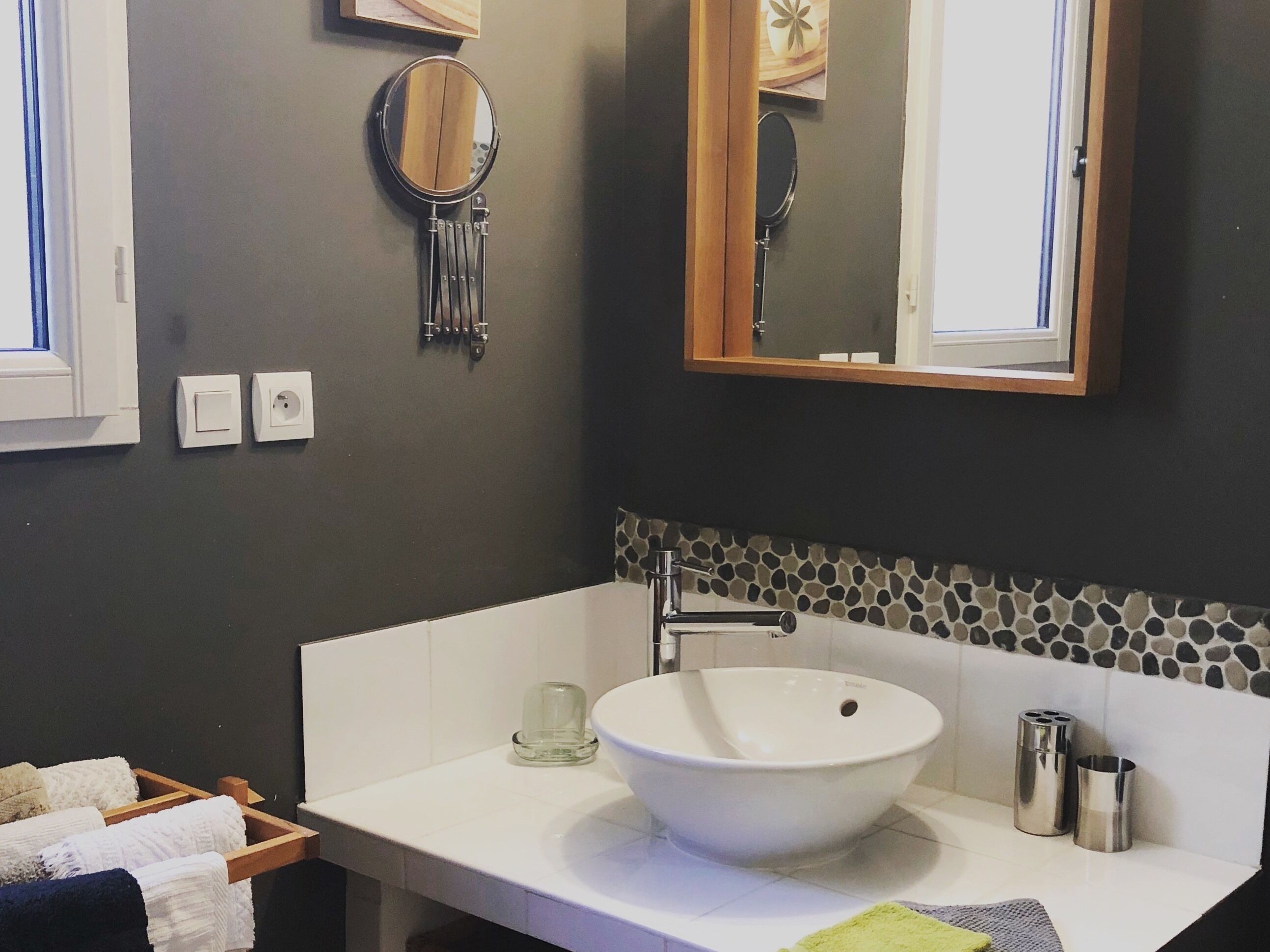 Ein Badezimmer mit einem großen, weißen Waschbecken, einem Spiegel und einer Rückwand aus Steinfliesen.