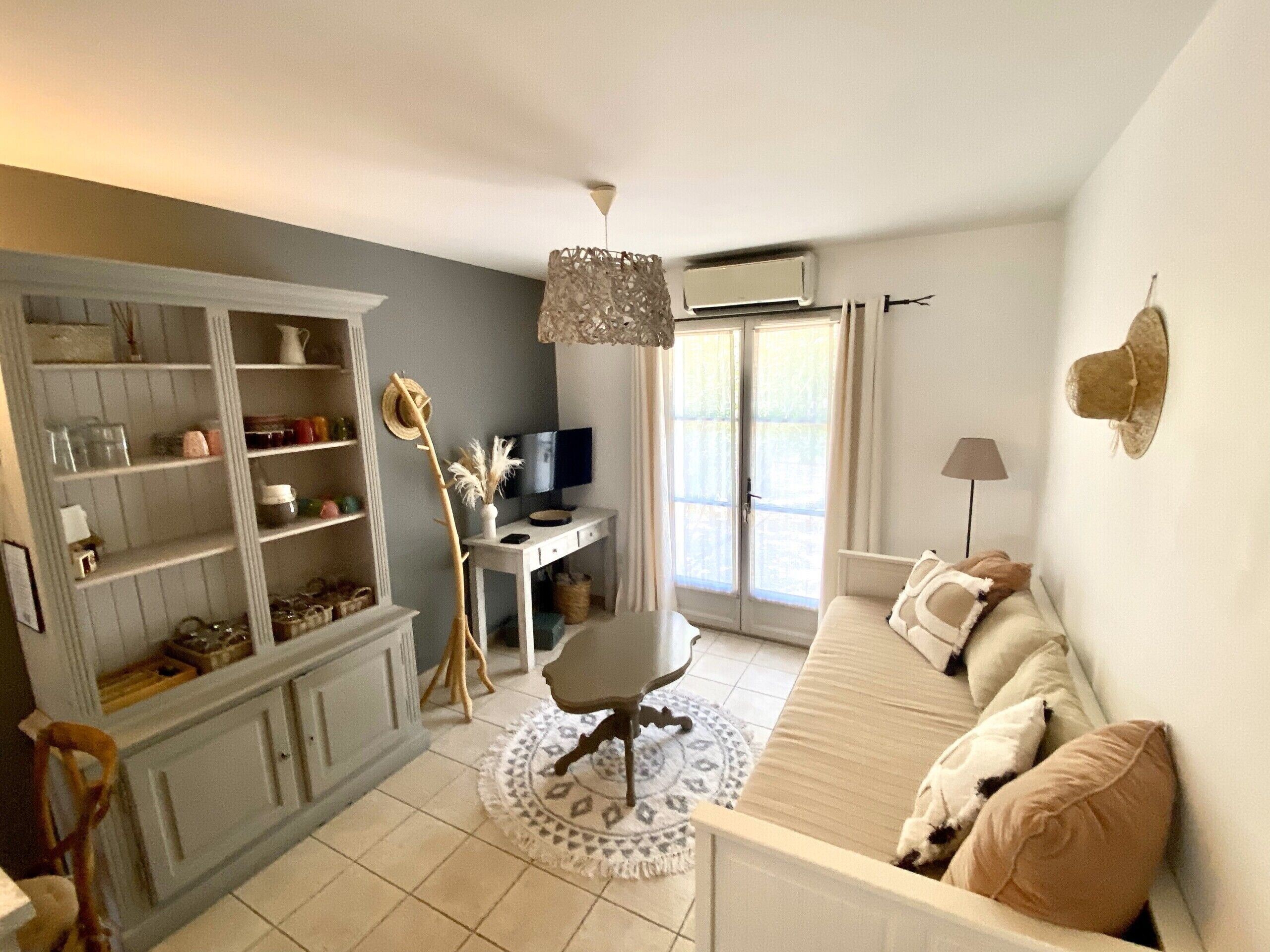 A living room with a sofa, a TV, a desk, and a bookshelf.