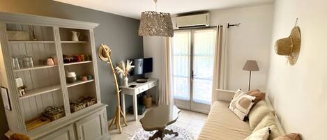 A living room with a sofa, a TV, a desk, and a bookshelf.