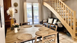 Un comedor con una mesa de madera, individuales tejidos y una escalera de madera.