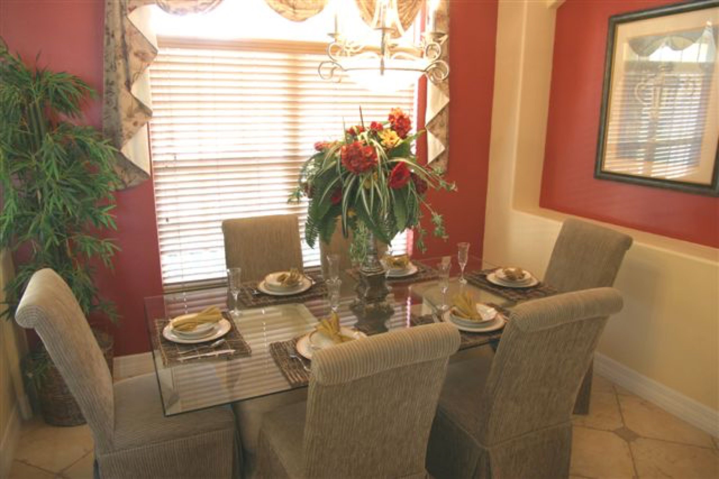 A dining area with a glass table set for four, surrounded by upholstered chairs.