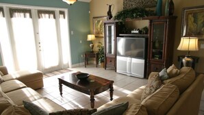 Un salon avec un canapé beige, une table basse en bois et un réfrigérateur.