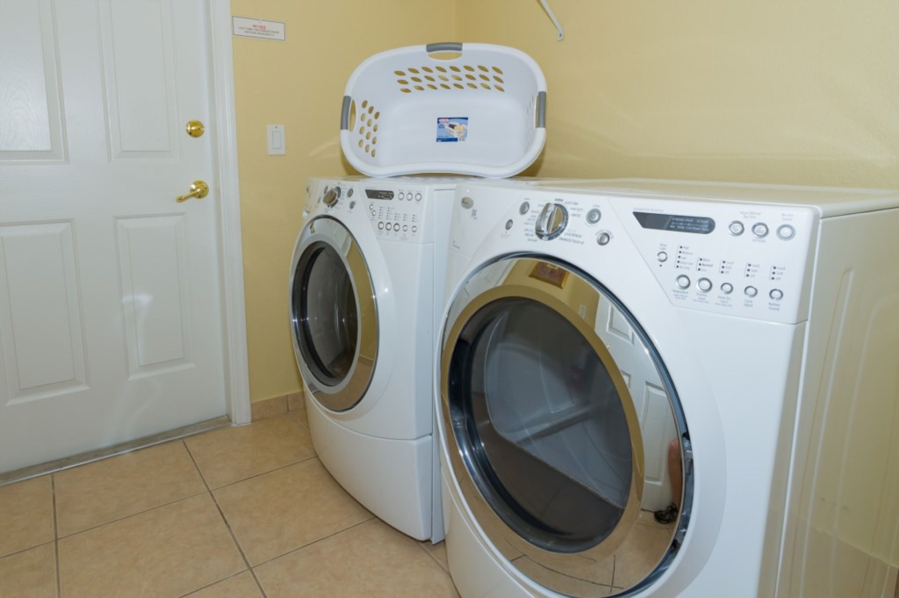 A laundry room with two front-loading washing machines and a white door with a brass handle.