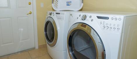 A laundry room with two front-loading washing machines and a white door with a brass handle.