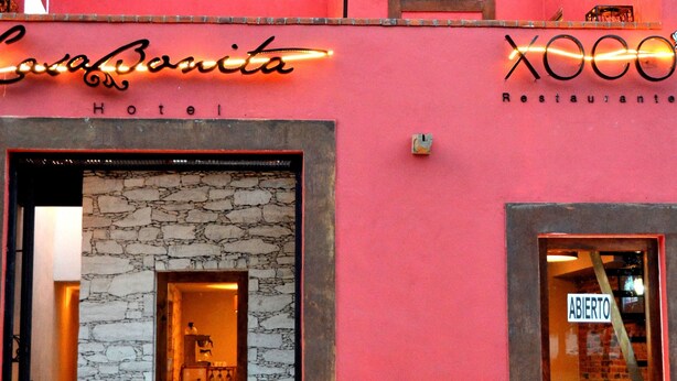 Um hotel com fachada de pedra, um letreiro de neon e entrada aberta.