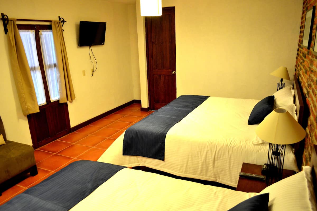 Een hotelkamer met twee bedden, een televisie, een deur en een stoel.