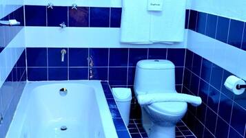 Un baño con bañera, inodoro y toallero.