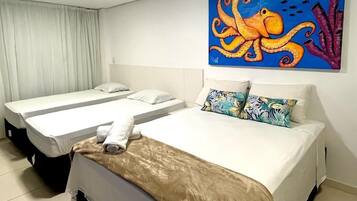 A hotel room with two single beds, a large painting of an octopus, and a view of the sea through the window.