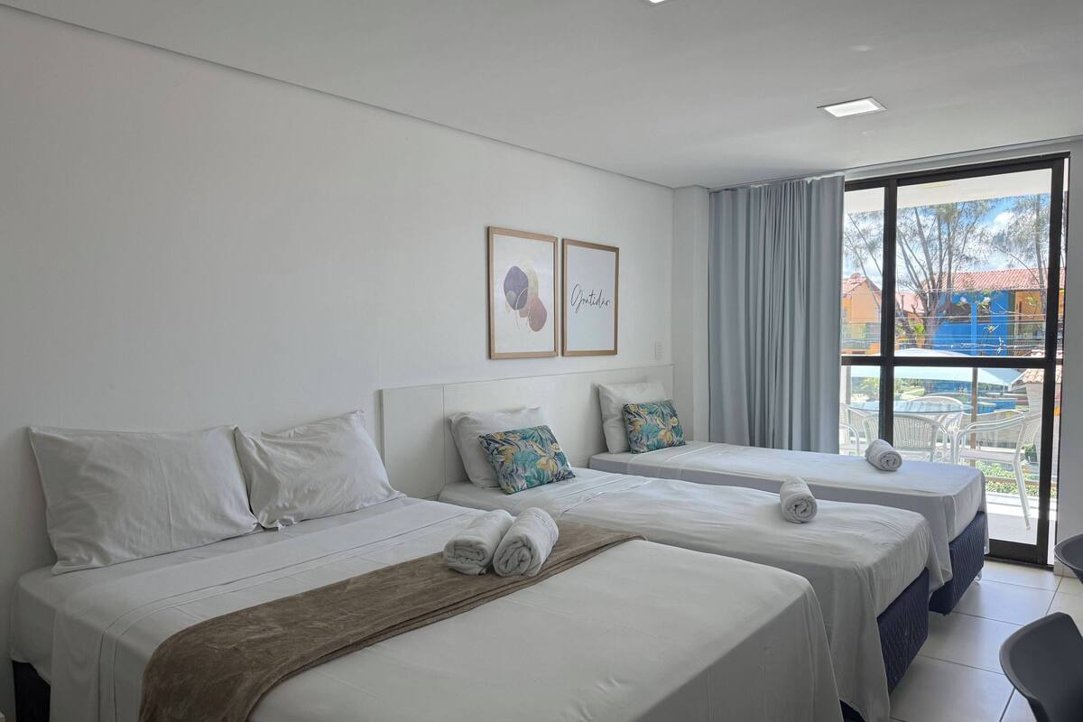 A hotel room with two beds, a large window with a view, and a ceiling light.