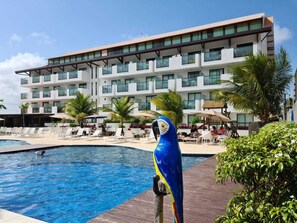 A modern hotel with a pool, palm trees, and a parrot statue. - Laguna Beach Flat by AFT (Ipojuca)