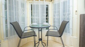 A corner dining area with a glass table and two chairs, surrounded by frosted glass windows with metal bars. - Columbus Heights Ocean View Large Studio (Ocho Rios)