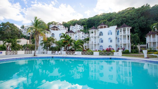 A resort with a swimming pool, white buildings, and lush greenery. - Columbus Heights Ocean View Large Studio (Ocho Rios)
