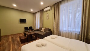 Une chambre d’hôtel avec deux lits, un canapé, une télévision et une table.