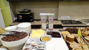 Un buffet proposant une variété d’aliments, notamment des céréales, du beurre, des confitures et des viennoiseries.