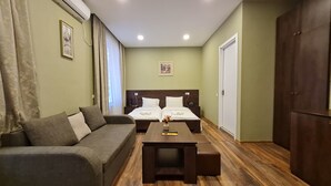 Une pièce comprenant un canapé, un lit avec deux oreillers, une petite table avec un vase et une armoire.