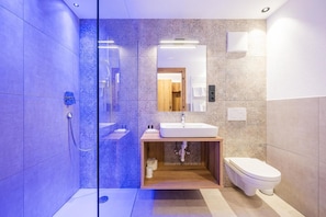 Une salle de bain moderne avec une douche à parois de verre, un lavabo avec un meuble-vasque en bois et des toilettes.