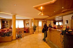 Un hall de hotel con mostrador de recepción, zona de estar y un espejo grande.