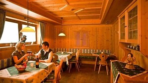 A wooden cabin interior with a dining area, a bench, and a small altar.