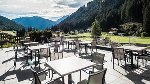 An outdoor patio with tables and chairs, overlooking a mountainous landscape. - Hotel & Restaurant Feldrand (Sarentino)
