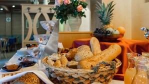A dining table with a basket of bread, a pitcher of juice, and a vase of flowers. - Hotel & Restaurant Feldrand (Sarentino)
