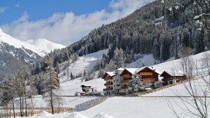 A snow-covered mountain landscape with a wooden lodge featuring multiple balconies and a ski lift in the background. - Hotel & Restaurant Feldrand (Sarentino)