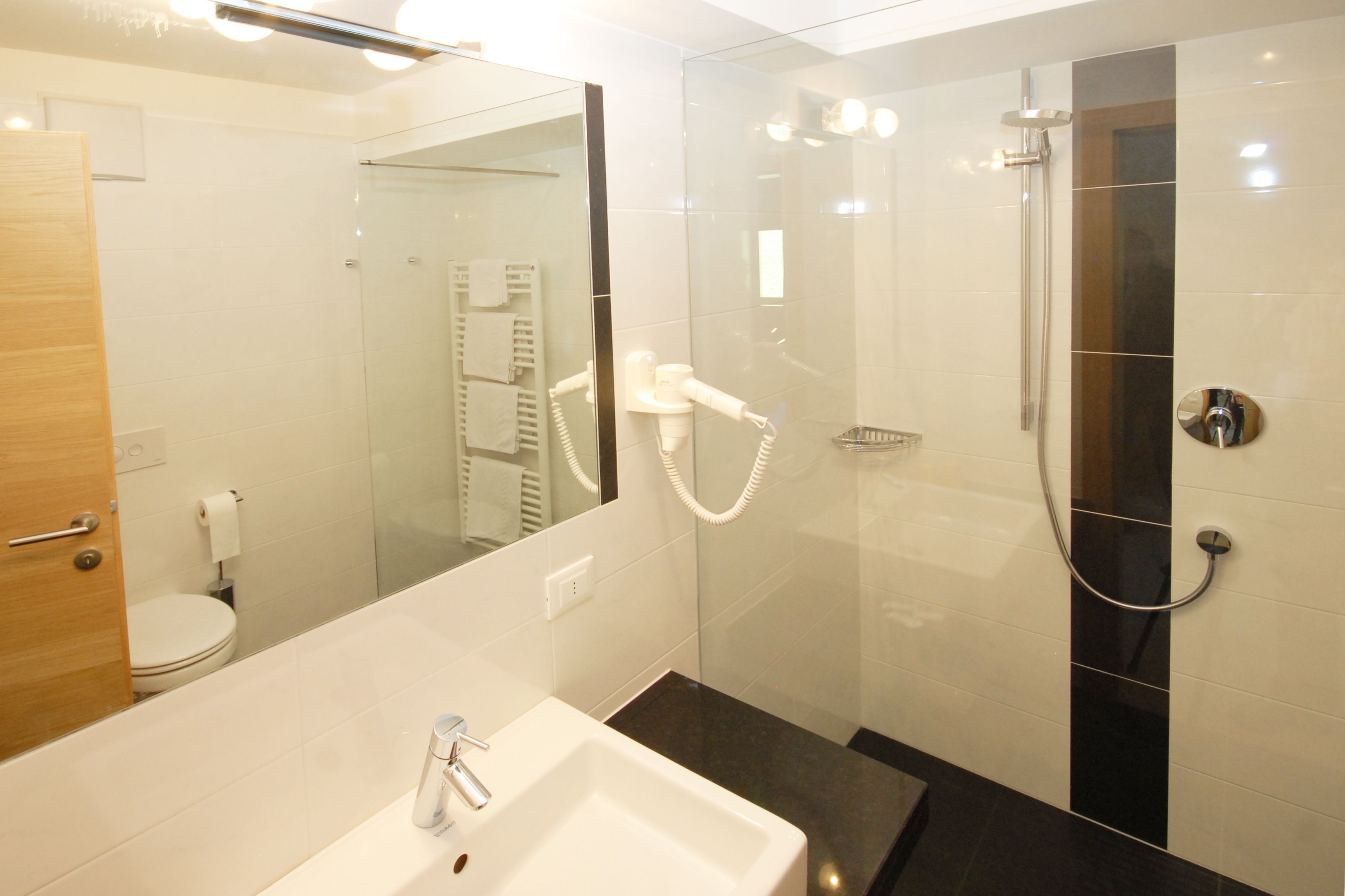 A modern bathroom with a glass-enclosed shower, a white sink, and a mirror.