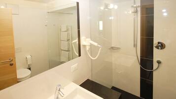 A modern bathroom with a glass-enclosed shower, a white sink, and a mirror.